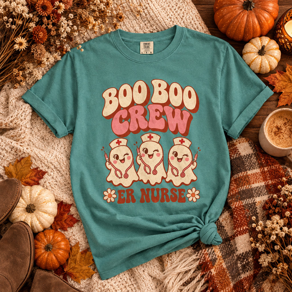 A teal short-sleeve t-shirt with a retro graphic on the front that reads 'BOO BOO CREW ER NURSE' in pink and orange lettering, featuring three cute cartoon ghosts dressed as nurses.