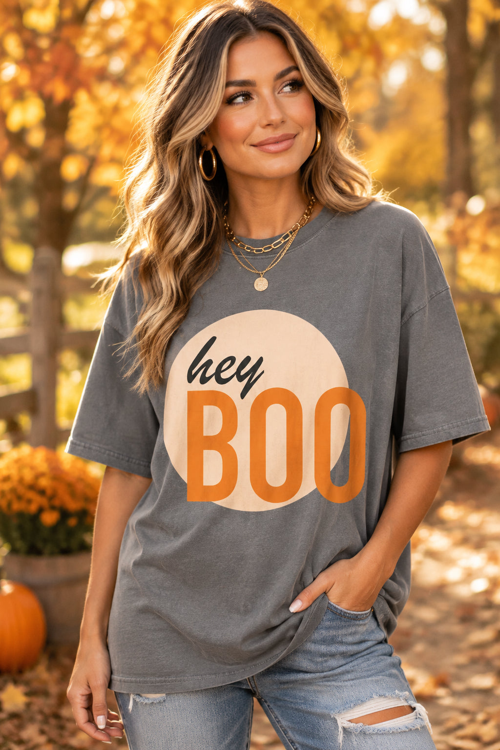 A gray short-sleeve crewneck t-shirt featuring a graphic print of a peach circle with the words 'hey BOO' in black and orange lettering, displayed on a clean white background.